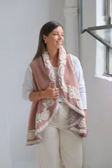 Chaleco abierto de textura suave, color rosa con diseño floral en relieve de color crema en los bordes y el interior. Presenta un corte holgado y fluido.