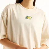 Remera oversize de color beige con cuello redondo y mangas cortas. Cuenta con un pequeño parche estampado en el centro del pecho con el logo de la marca en estilo colorido.
