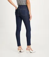 Pantalón skinny jeans azul oscuro con trabillas en la cintura, bolsillos y detalle de pespuntes contrastantes. La pieza también tiene dos botones dorados a cada lado de la barra.