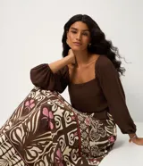 Vestido midi de viscosa con estampado de follaje, escote cuadrado y mangas largas con puños elásticos. Presenta un corte evasé y un lazo fino en la cintura.