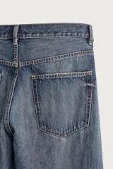 Jeans de denim de algodón en color azul con efecto desgastado, tiro medio y corte recto de ajuste holgado (loose fit). Cuenta con diseño clásico de cinco bolsillos y cierre frontal con cremallera y botón.