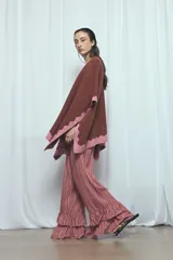 Poncho marrón con detalles de bordes ondulados en color rosado, confeccionado en mezcla de acrílico, poliéster y elastano, de diseño abierto y mangas amplias.