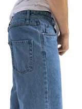 Bermuda de jean de corte oversized con diseño de cinco bolsillos, cierre de botón y cremallera, en un tono azul medio clásico.