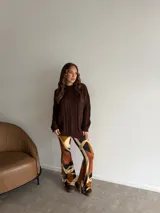 Buzo de punto en color beige, con diseño de trenzas verticales en el frente, cuello redondo y mangas largas con puños acanalados.