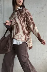 Sweater de tejido de punto con diseño estampado abstracto en tonos marrones y beige, de corte oversize, cuello redondo y mangas largas con puños acanalados.