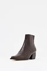 Bota corta estilo texano de cuero color chocolate con textura de cocodrilo y detalles de costuras decorativas. Cuenta con taco cuadrado y punta fina.