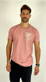 Remera de algodón color rosa con cuello redondo y mangas cortas. Presenta un diseño gráfico estampado en el pecho que combina una rosa con una silueta facial y texto.