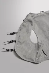 Chaleco deportivo técnico y ligero de color gris, diseñado con tejido de malla transpirable, múltiples bolsillos frontales elásticos, cierres de cordón ajustable y detalles reflectantes, ideal para running y actividades al aire libre.