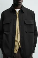 Sobrecamisa relaxed fit color beige con tejido elástico, cuello solapa, manga larga con puños abotonados, bolsillos de plastrón con solapa en el pecho, bolsillos laterales de vivo en la cadera y cierre frontal de botones.