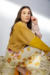 Buzo amarillo mostaza de tejido de punto acanalado, con mangas largas acampanadas y puños en color rosa claro.