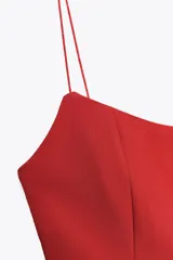 Top negro de escote redondo con tirantes finos y diseño peplum.