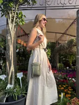 Bandolera compacta color rosado, con correa regulable y desmontable. Tiene apertura superior, bolsillo frontal con cierre y detalle de borla, y bolsillo trasero sin cierre. El interior está forrado en tela y cuenta con un bolsillo adicional.