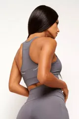 Top deportivo de alto rendimiento con diseño de espalda nadador, confeccionado en tejido técnico con protección UV50+. Presenta un bolsillo interno en el forro frontal y detalles reflectivos.