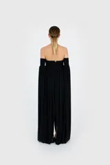 Vestido largo negro de silueta fluida con escote palabra de honor, cuerpo fruncido elástico y mangas largas caídas con paneles amplios de tejido.