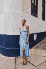 Vestido midi de algodón con estampado de lunares blancos sobre fondo celeste. Presenta cuello halter con cierre de botones y espalda descubierta, con un corte evasé fluido.