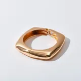 Brazalete rígido dorado con forma cuadrada y cierre de resorte.
