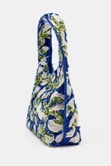 Bolso de mano mini con diseño floral bordado en abalorios y lentejuelas en tonos azul, verde y blanco. Cuenta con asa integrada, forro interior con bolsillo y cierre mediante botón imantado.