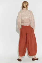 Pantalón balloon de tela liviana y fluida, color rojo terracota, con cintura elastizada, cordón de ajuste, pinzas frontales y diseño abullonado en los tobillos.