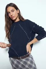 Sweater de tejido suave color azul marino, con diseño de líneas bordadas en contraste que forman un patrón geométrico. Presenta cuello redondo, mangas largas y un calce relajado.