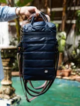 Bolso matero azul marino con diseño capitoneado, correa ajustable y asa superior.