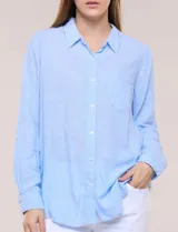Camisa de lino marca Dash, color beige, con cuello con solapa, escote en V y cierre frontal con botones. Presenta mangas largas regulables con presilla y botón, y un bolsillo aplicado en el pecho.