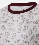 Pijama largo de dos piezas confeccionado en tejido acanalado de poliéster y viscosa. Consta de una remera de manga larga con cuello redondo en contraste y un pantalón con cintura elástica y puños ajustados. Ambos presentan una estampa integral con motivos de Winnie The Pooh en tono oscuro sobre fondo claro.