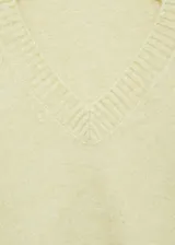Jersey de punto color amarillo claro, con cuello en pico y diseño recto de manga larga con puños acanalados.