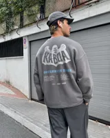 Buzo gris oscuro con efecto acid wash, corte regular fit y cuello redondo. Presenta una estampa grande en la espalda con diseño de calavera, el texto "Kaboa" y detalles de fechas de tour en tonos claros.