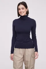 Polera de tejido de punto fino en color azul marino, con cuello alto y mangas largas. Presenta un ajuste al cuerpo y terminaciones acanaladas en cuello, puños y ruedo.