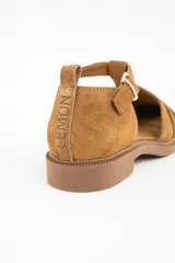 Sandalia tipo cangrejera de gamuza color camel, con diseño de tiras entrelazadas, puntera cerrada y cierre con hebilla metálica lateral.