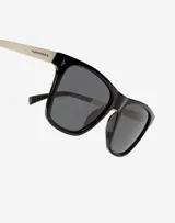 Lentes de sol unisex con marco cuadrado negro, patillas metálicas plateadas y cristales polarizados oscuros.