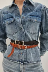 Cinturón de cuero vacuno trenzado en color negro, con hebilla metálica plateada de diseño rectangular con detalles de tachas.