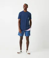 Bermuda de baño para hombre, color azul con recortes en bloques de color (azul más claro y rosa pálido). Presenta cintura elástica con cordón de ajuste y es de tejido plano de poliamida.