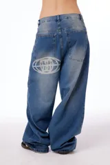 Pantalón de jean oversized de tiro bajo, color azul lavado, con grabado láser de la palabra "Blkmba" en el frente y "Worldwide" en la parte trasera.