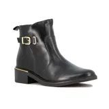 Bota de caña baja en cuero negro, con taco bajo cuadrado y detalle de hebilla dorada lateral. Presenta un detalle metálico dorado en la base del talón.