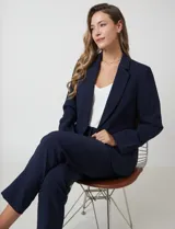 Blazer sastrero entallado color beige, con cuello de solapa, cierre frontal con un botón a tono y hombreras estructuradas. Presenta bolsillos laterales con solapa y forro interno.