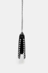 Cartera bandolera de gamuza negra con detalles de tachas metálicas plateadas en todo el borde. Cuenta con cierre de cremallera y correa de cadena metálica larga y extraíble.