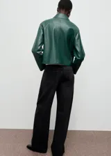 Chaqueta corta de efecto piel en color verde, con cuello de solapa, cierre frontal de botones y dos bolsillos de parche con solapa en la parte delantera.