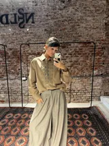 Camisa de algodón color beige con detalles de bordado tipo broderie en el frente y en los hombros, de corte clásico y manga larga.