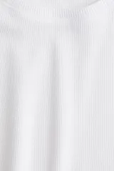 Remera blanca de punto canalé, corte ajustado, cuello redondo y mangas cortas.