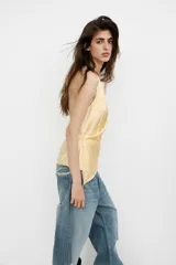 Top de tejido satinado con cuello halter y escote en pico cruzado. Presenta un diseño de espalda descubierta y bajo asimétrico con cierre lateral.