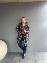 Abrigo de corte trench con estampado de tartán en tonos negro y gris. Presenta solapas amplias, bolsillos frontales y diseño abierto.