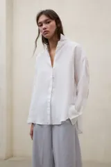Camisa Daria holgada de lino blanco, con cuello camisero, cierre frontal de botones y mangas largas.