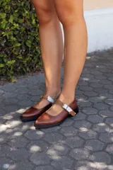 Zapato marrón de cuero con punta fina, tira sobre el empeine con hebilla y detalle de cuero con estampado animal.