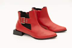 Botín de cuero rojo con elásticos laterales negros, aplique de hebilla metálica y taco cuadrado bajo. Cierre con cremallera lateral.