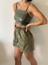 Top negro de cuerina con breteles finos y nudo central que deja ver parte del abdomen.