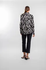 Camisa de manga larga con estampado geométrico de ondas en blanco y negro, cuello camisero y cierre frontal de botones.