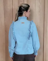 Camisa de denim negro con cuello alto, cierre frontal de botones y detalles de volados en el frente y puños.