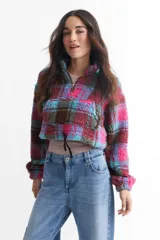 Buzo corto de corderito con estampado a cuadros en tonos marrón, rosa, celeste y violeta. Tiene cuello alto con cierre de cremallera y cordón ajustable en la cintura.