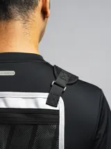 Bolso de pecho táctico color gris claro con detalles en negro, con correas ajustables y hombreras de neopreno. Cuenta con tres compartimentos: uno trasero de red y dos frontales con cierre.